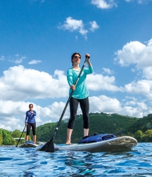 A man and woman use stand-up paddleboards on a sunny day.
