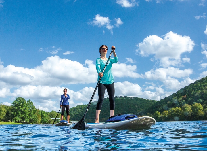 A man and woman use stand-up paddleboards on a sunny day.