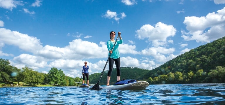 A man and woman use stand-up paddleboards on a sunny day.
