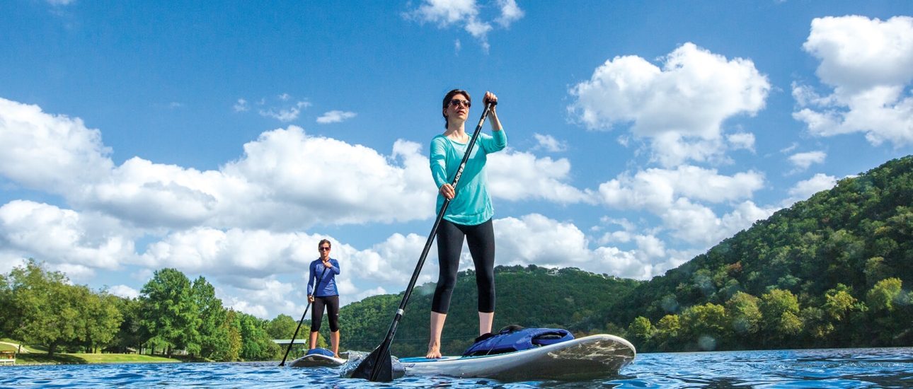 A man and woman use stand-up paddleboards on a sunny day.