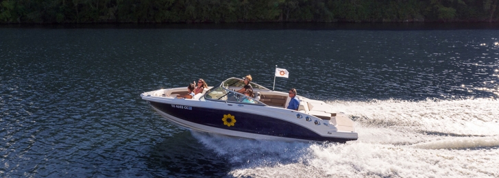 A family skims across the water in a speedboat with the Lake Austin Spa Resort logo on the side.