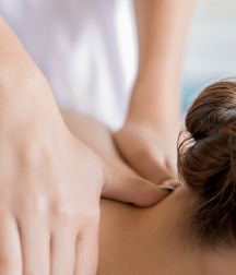 An up-close shot of a woman receiving a neck massage from a professional masseuse.