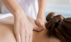 An up-close shot of a woman receiving a neck massage from a professional masseuse.