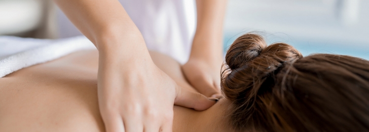 An up-close shot of a woman receiving a neck massage from a professional masseuse.