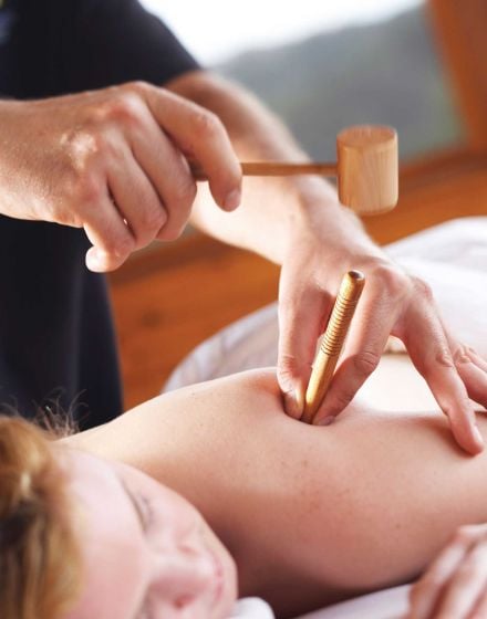 a woman receiving a massage with wooden tools