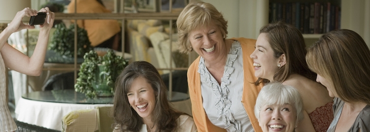 A group of women pose for a photo all smiling and look at one another.