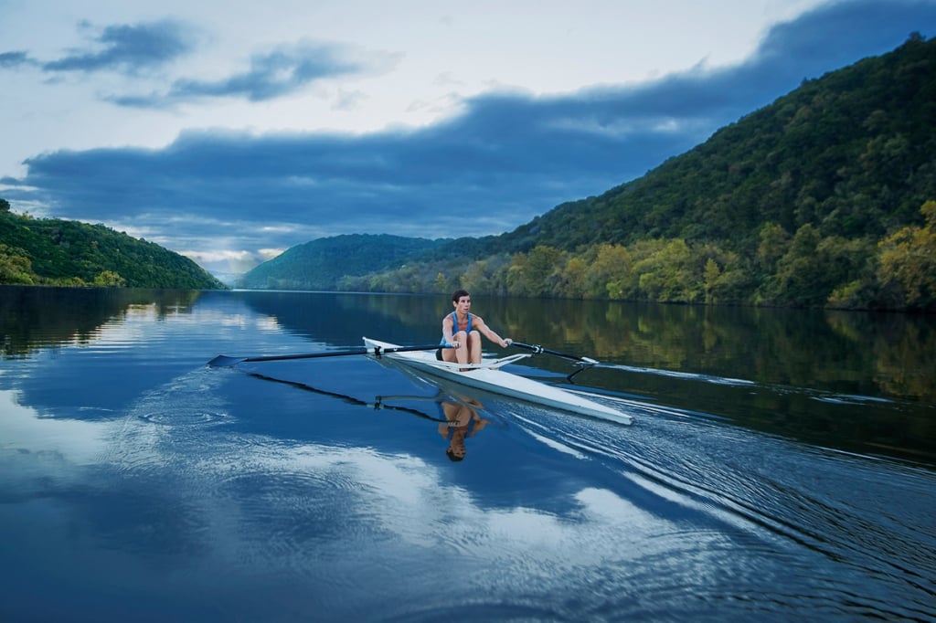 A guest glides across the water of Lake Austin in a single scrull rowing boat.