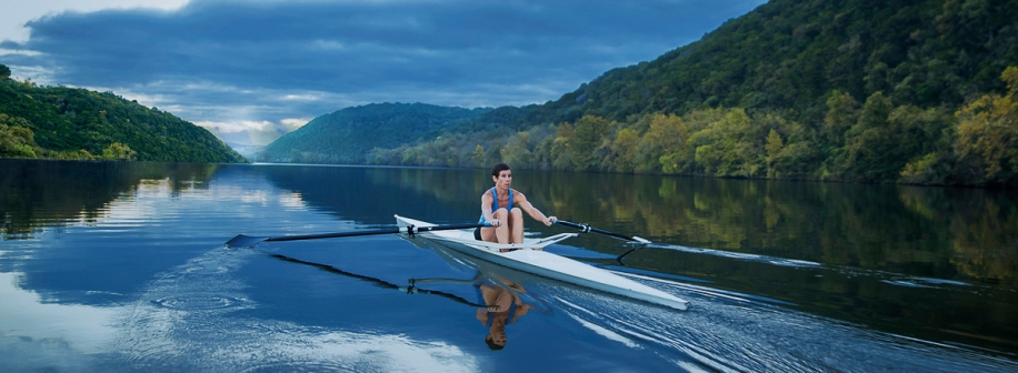 A guest glides across the water of Lake Austin in a single scrull rowing boat.