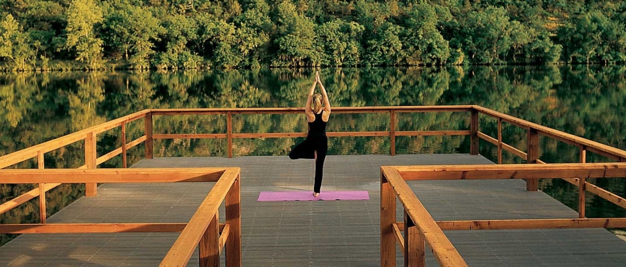 A woman practicing yoga alone on the dock at Lake Austin overlooking the water