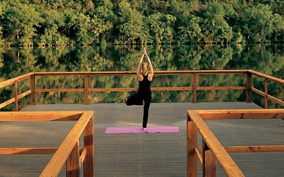 A woman practicing yoga alone on the dock at Lake Austin overlooking the water