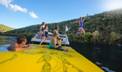 A woman jumping into Lake Austin while her friends smile and watch from the boat.