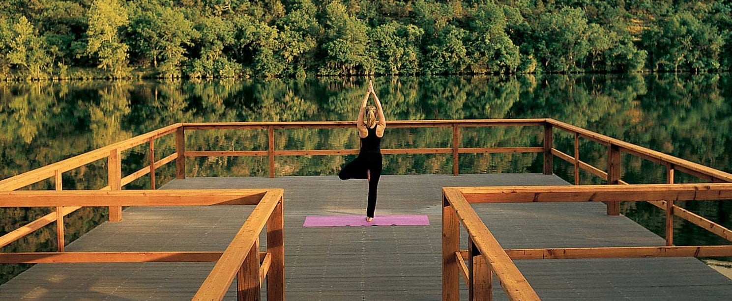 A woman practicing yoga alone on the dock at Lake Austin overlooking the water