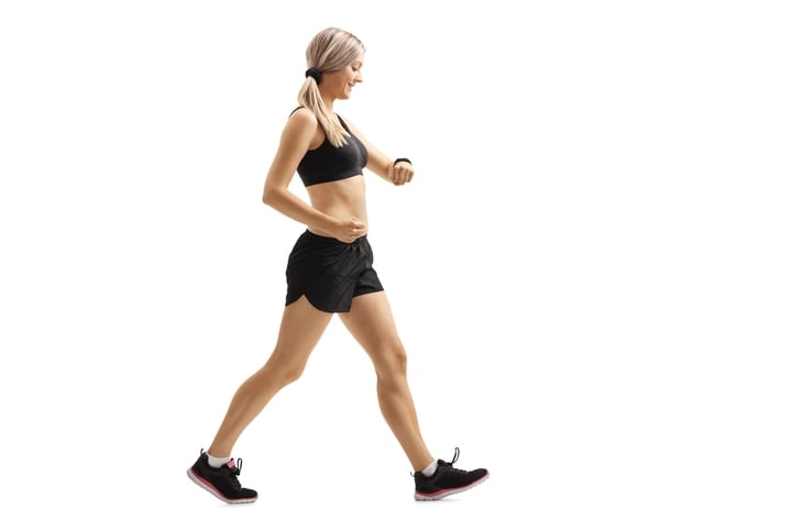 Full length profile shot of a woman walking and checking her sports watch isolated on white background