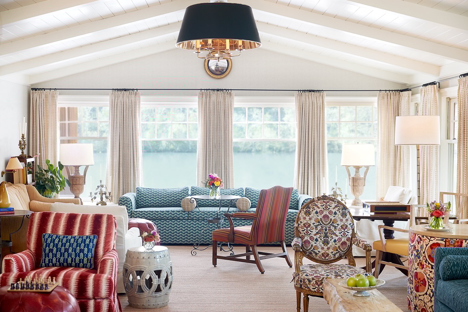 Couches and chairs in front of the floor-to-ceiling and lake-facing living room windows.