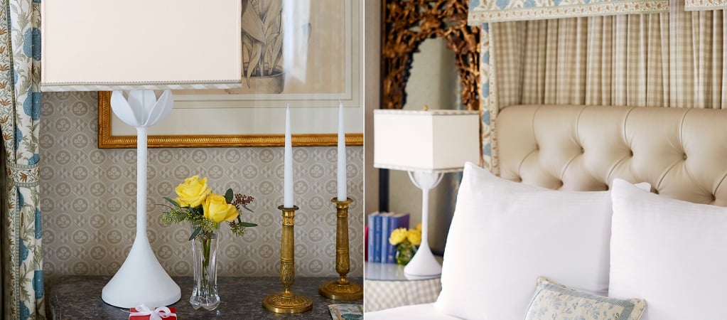 A close-up of a bed with white bedding and a tufted headboard, with a nightstand and lamp in the foreground.
