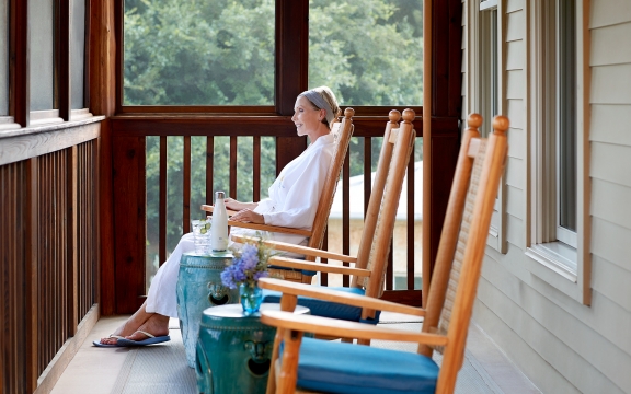 Woman sitting in a rocking chair on the porch of the Blue Room