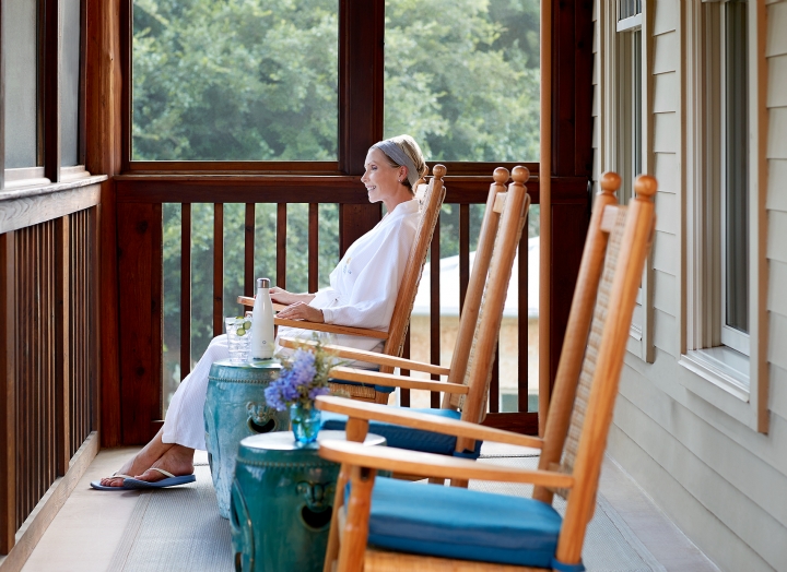 Woman sitting in a rocking chair on the porch of the Blue Room