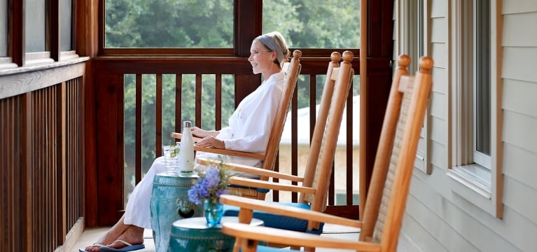 Woman sitting in a rocking chair on the porch of the Blue Room