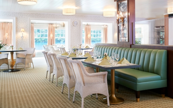 Long green bench and white wicker chairs inside the dining room