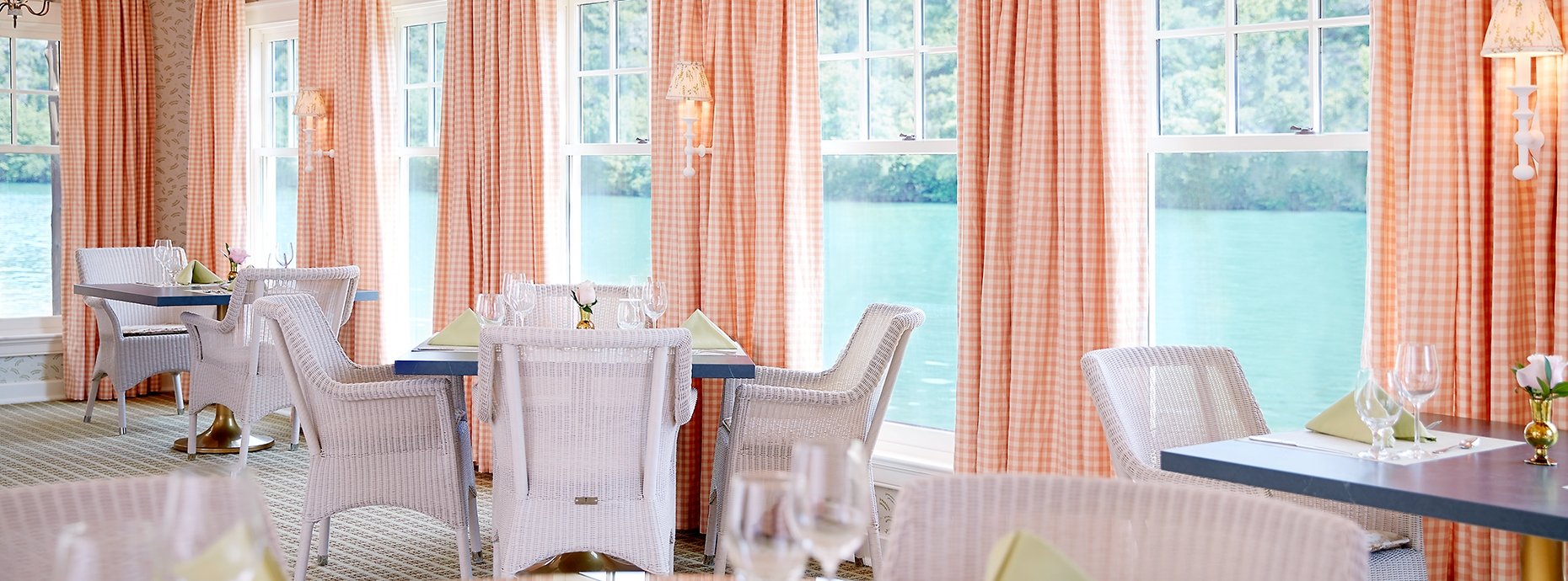 White wicker chairs around set tables in the dining room