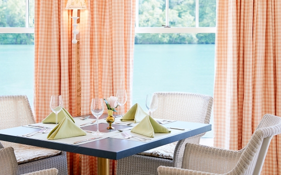 White wicker chairs around a set table in the dining room