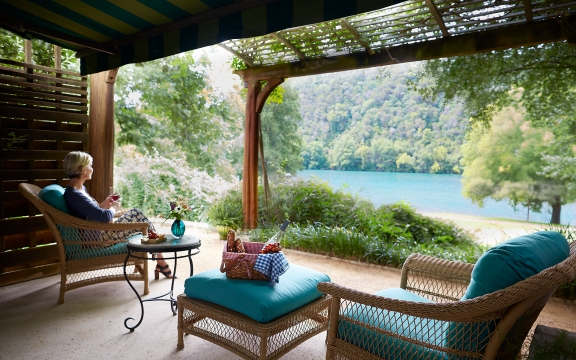 A woman enjoying the view and a glass of wine on the front porch of the Luxury LakeView room