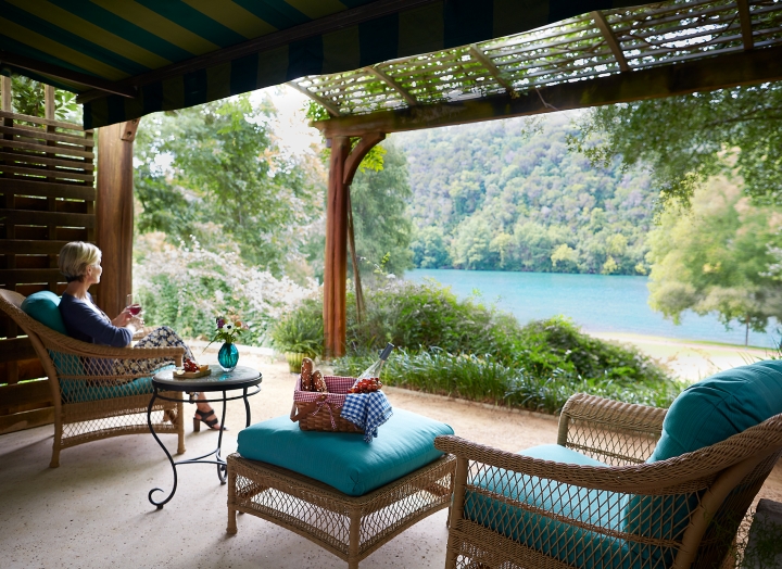 A woman enjoying the view and a glass of wine on the front porch of the Luxury LakeView room