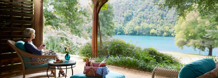 A woman enjoying the view and a glass of wine on the front porch of the Luxury LakeView room