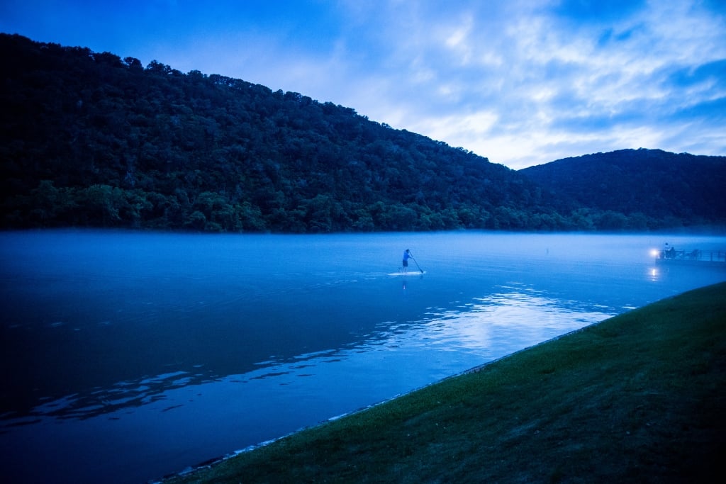 A man on a stand up paddleboard on Lake Austin at dusk