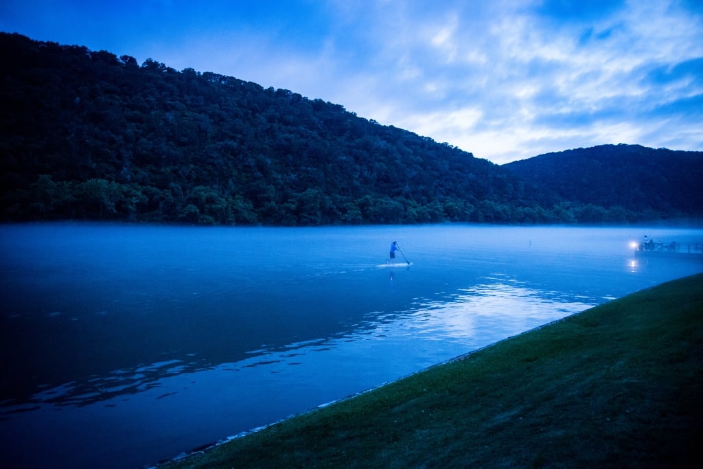 A man on a stand up paddleboard on Lake Austin at dusk