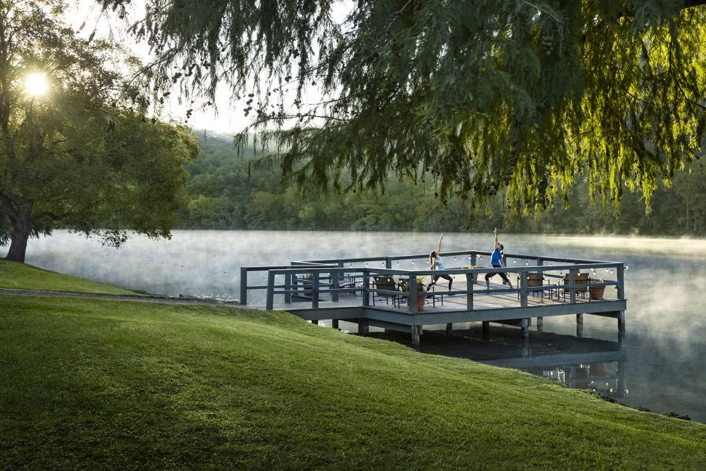 Woman and instructor doing yoga on dock in the early morning with fog coming off the lake at Lake Austin Spa Resort