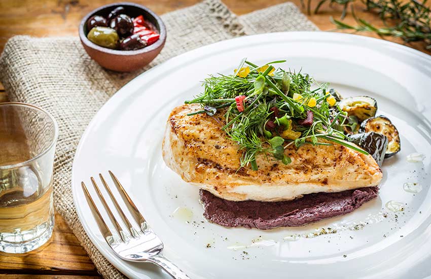 grilled chicken with green garnish and sauce below