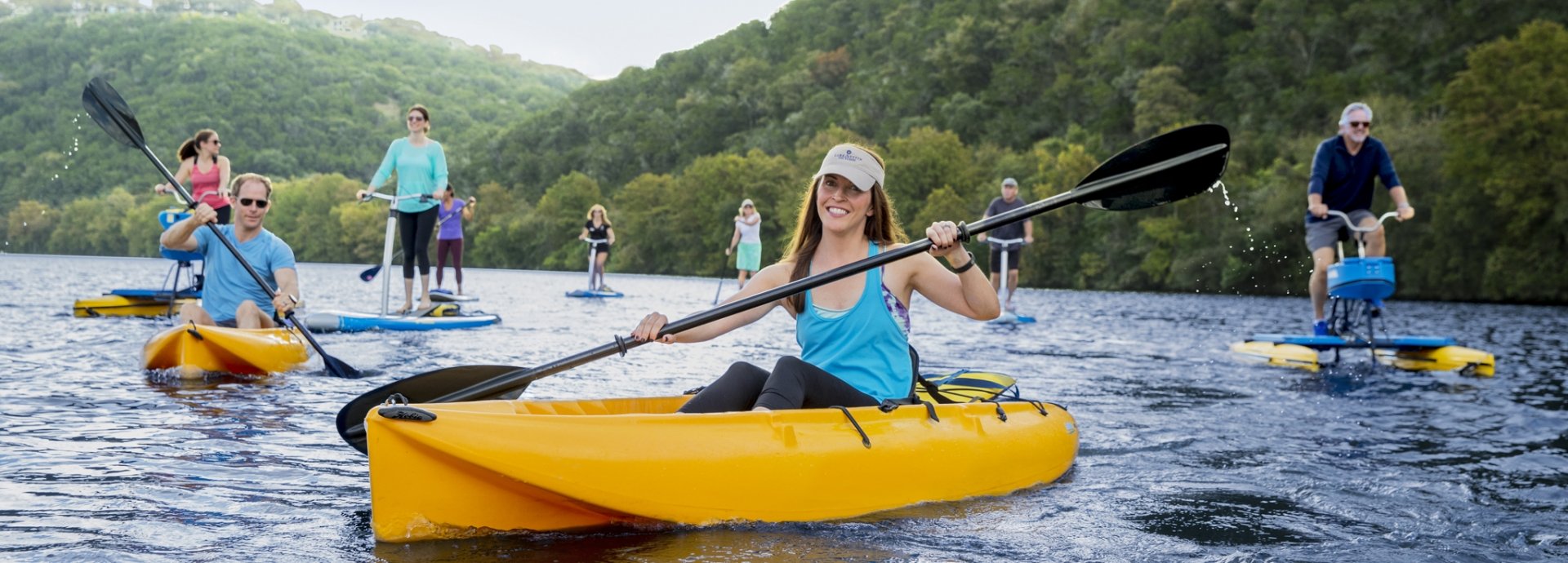 Group of people on the water in kayaks, paddleboards and different watercraft