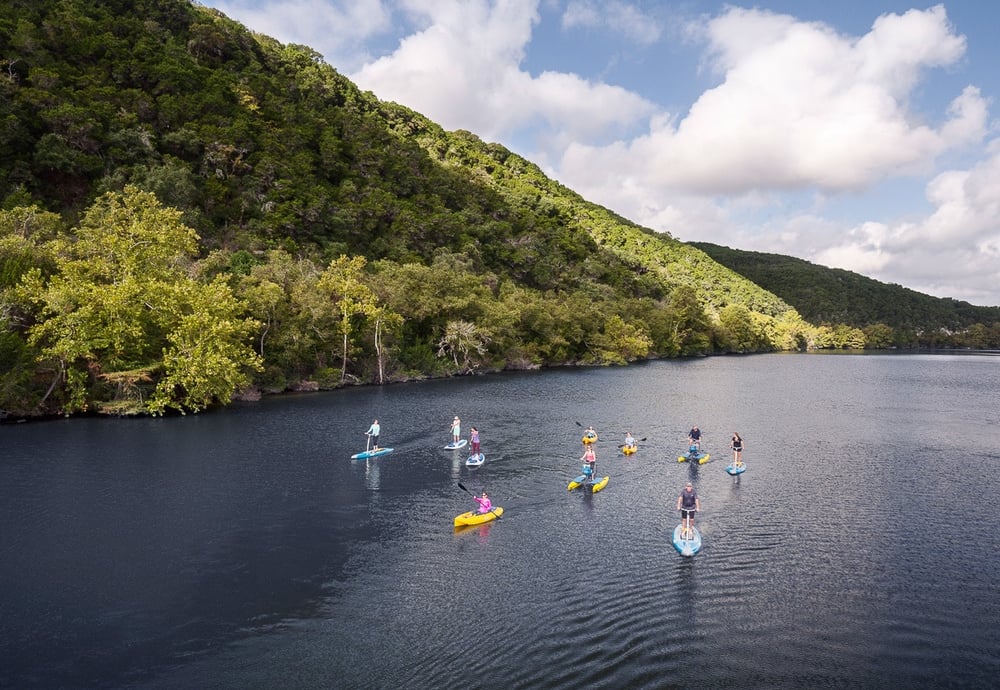 group of people on various kayaks and paddle boards on Lake Austin