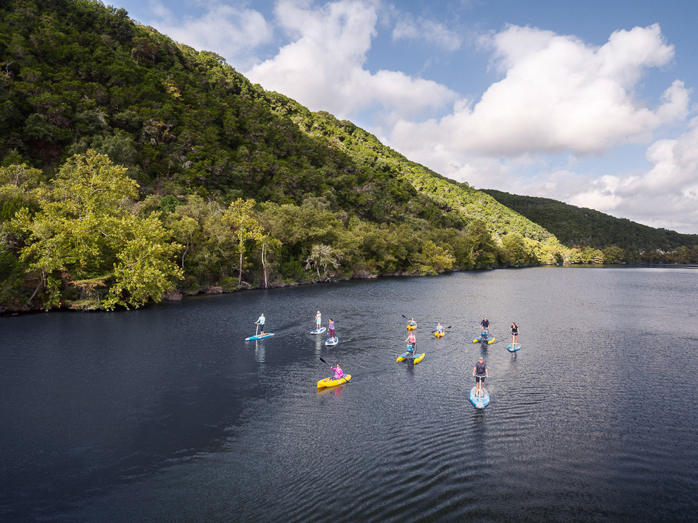 group of people on various kayaks and paddle boards on Lake Austin