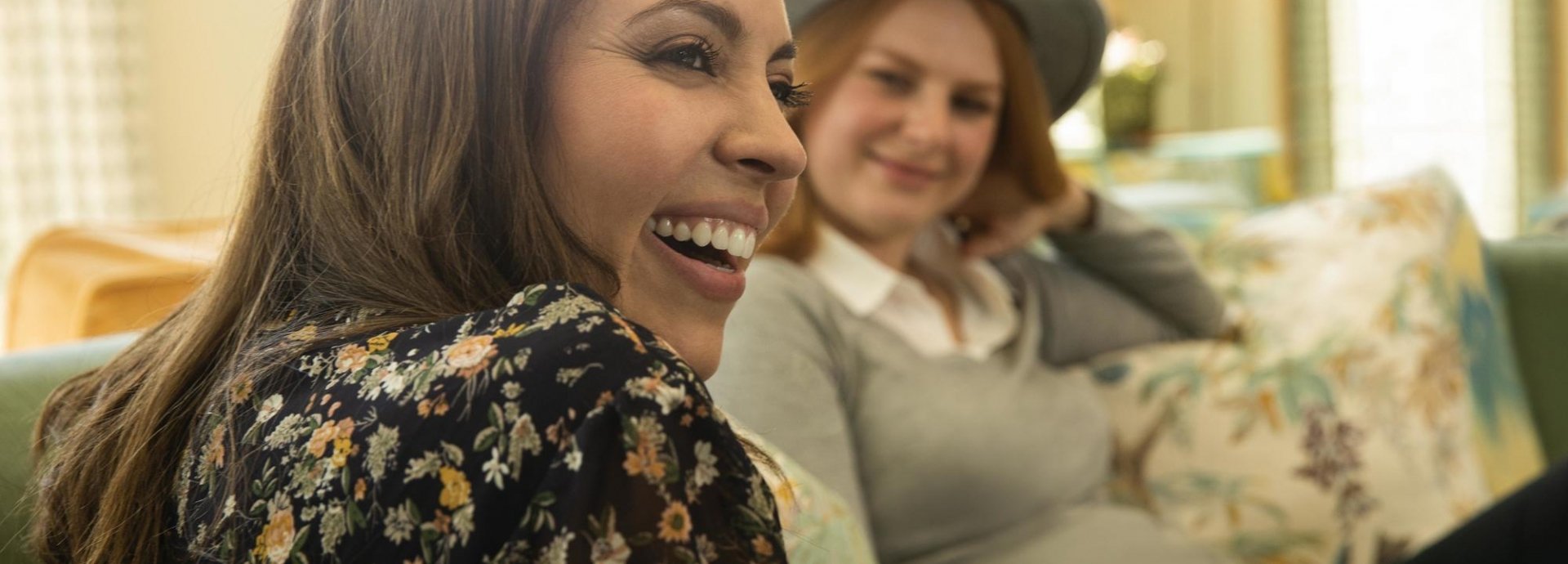 two women laughing on a sofa
