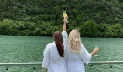 Two women in robe looking at the lake holding mimosas