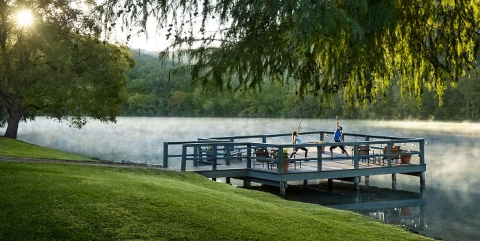 A serene lake scene with a deck and people practicing yoga