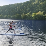 two women on stand up paddle boards doing yoga