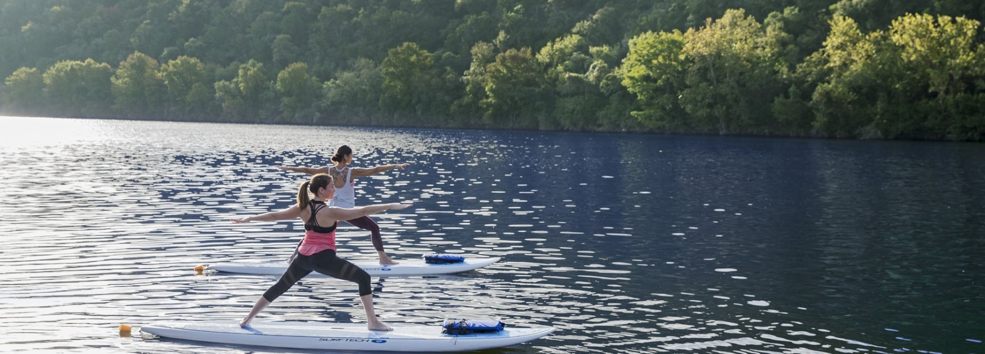 two women on stand up paddle boards doing yoga