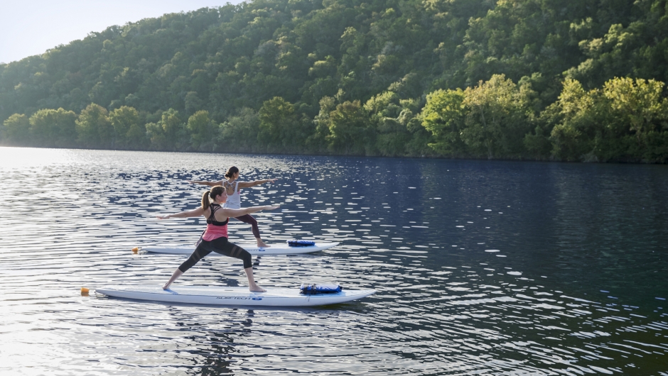 two women on stand up paddle boards doing yoga