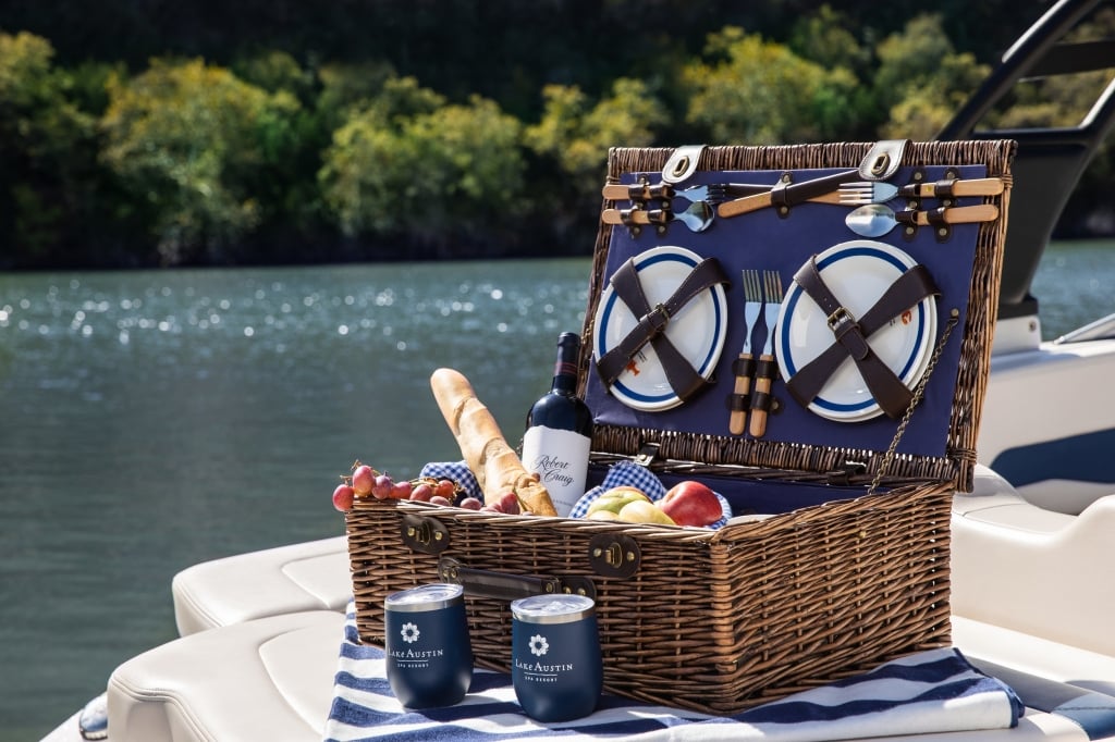 picnic basket and branded tumblers sitting on back of boat floating in water