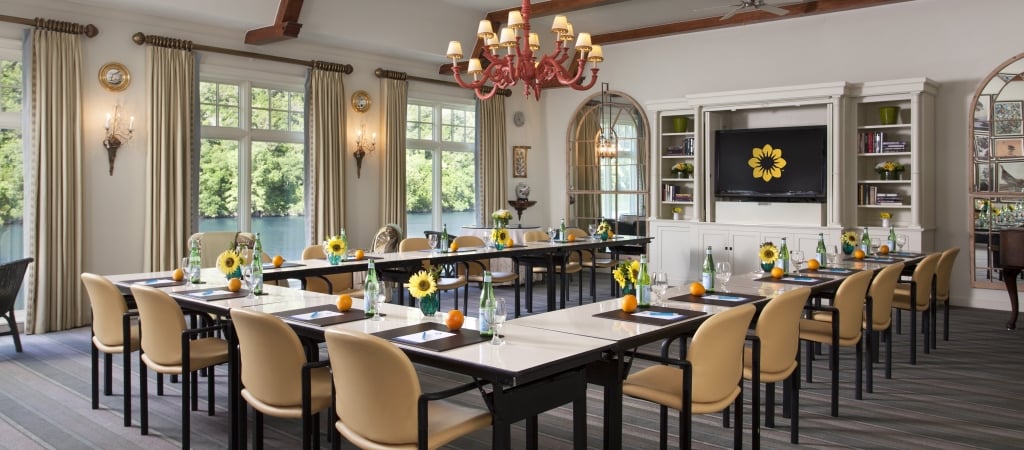 A well-lit meeting room with a long table, chairs, and a chandelier