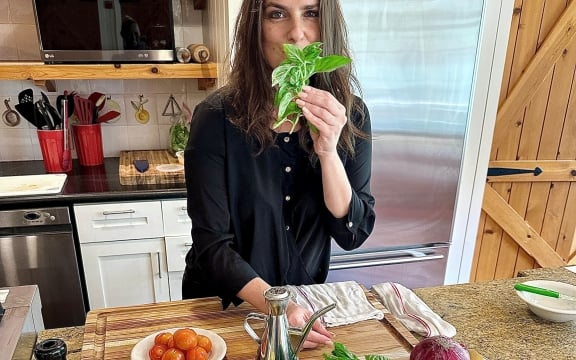Chef Rita standing with ingredients for her dish displayed on the table