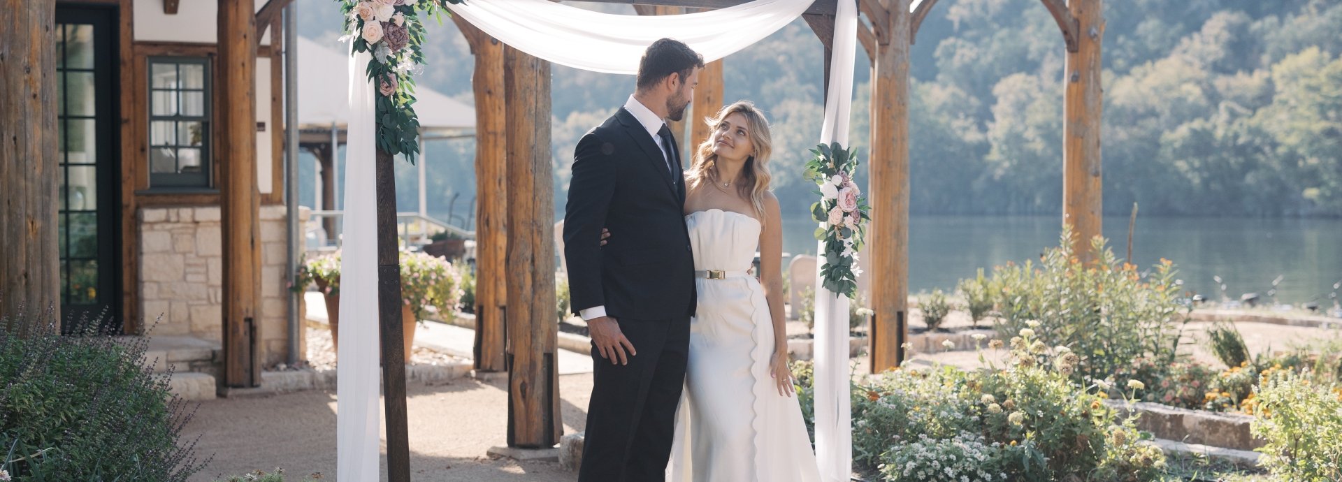 Bride and groom standing in front of a garden library, posing for a wedding photo