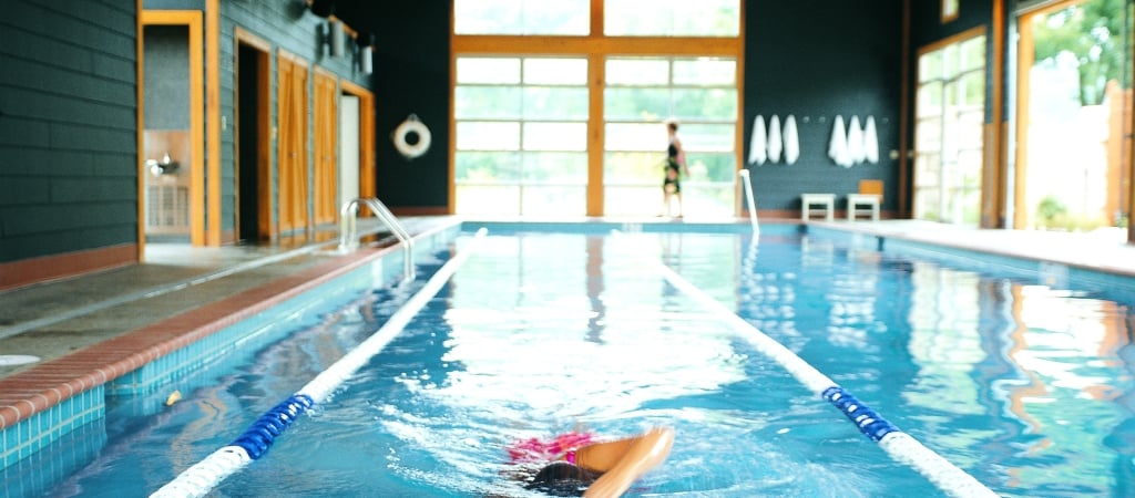 a person swimming in an indoor pool with lanes