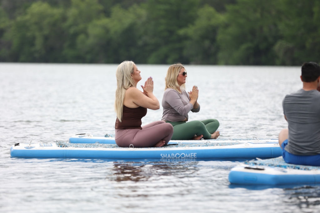 ladies sitting doing yoga on paddleboards in the sea