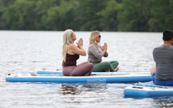 ladies sitting doing yoga on paddleboards in the sea