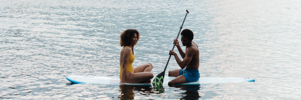 two people sitting on a paddleboard in a lake